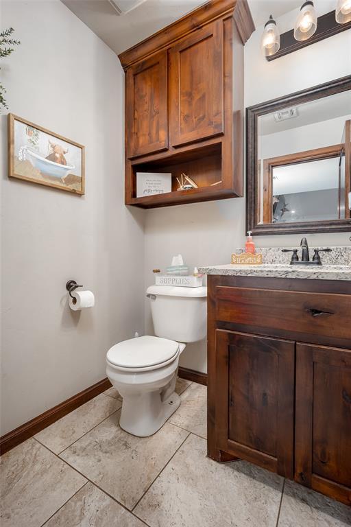 bathroom featuring baseboards, tile patterned flooring, toilet, and vanity