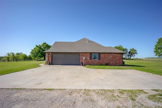 view of side of home with a yard, brick siding, an attached garage, and fence