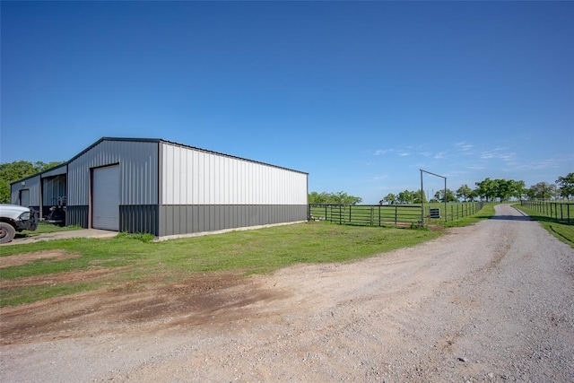 view of outdoor structure featuring fence, an outdoor structure, and driveway