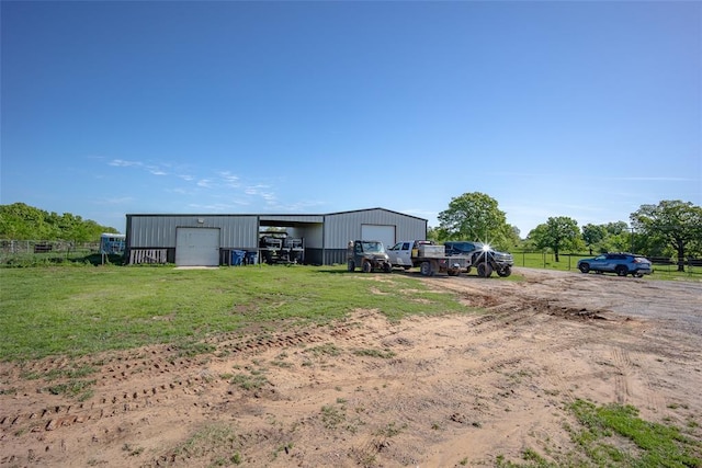 view of yard featuring fence, a pole building, an outdoor structure, and a garage