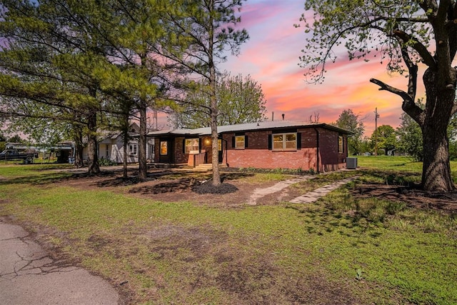 exterior space with a lawn, brick siding, and central AC