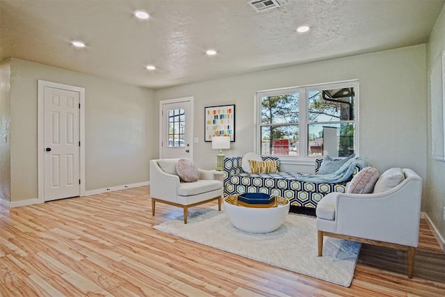 living room with wood finished floors, visible vents, and baseboards