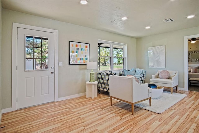 living room with baseboards, light wood-style flooring, visible vents, and recessed lighting