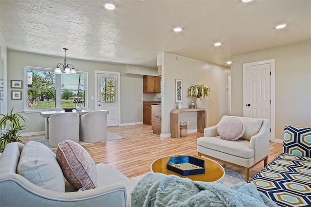 living area with light wood finished floors, baseboards, an inviting chandelier, and recessed lighting