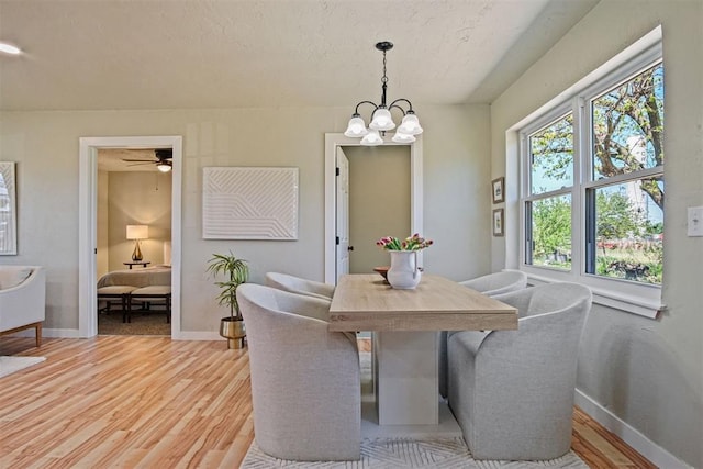 dining space with light wood-style flooring, baseboards, and an inviting chandelier
