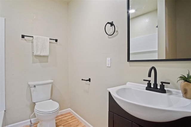 bathroom featuring toilet, vanity, wood finished floors, and baseboards