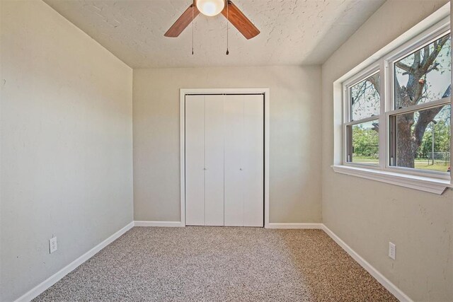 unfurnished bedroom with baseboards, carpet flooring, a textured ceiling, and a closet