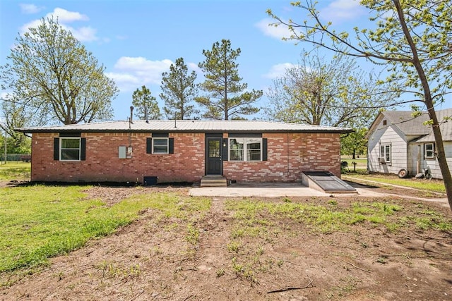rear view of house with a lawn, brick siding, a patio area, and entry steps