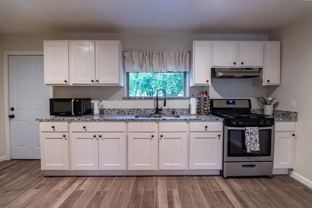 kitchen featuring black microwave, a sink, gas stove, light wood finished floors, and under cabinet range hood