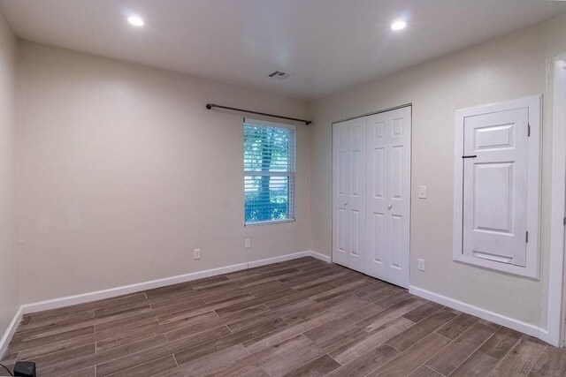 unfurnished bedroom featuring dark wood-type flooring, baseboards, visible vents, and a closet