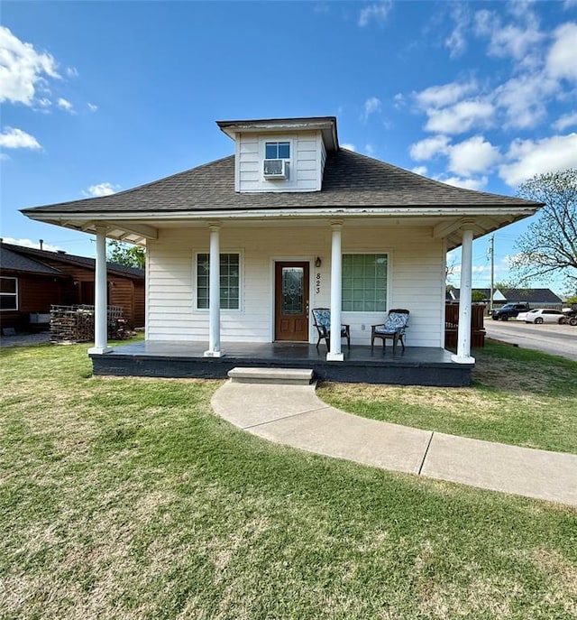 bungalow-style home featuring a front lawn, roof with shingles, a porch, and cooling unit