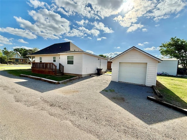 view of front of property featuring driveway, an outbuilding, a front yard, and a garage