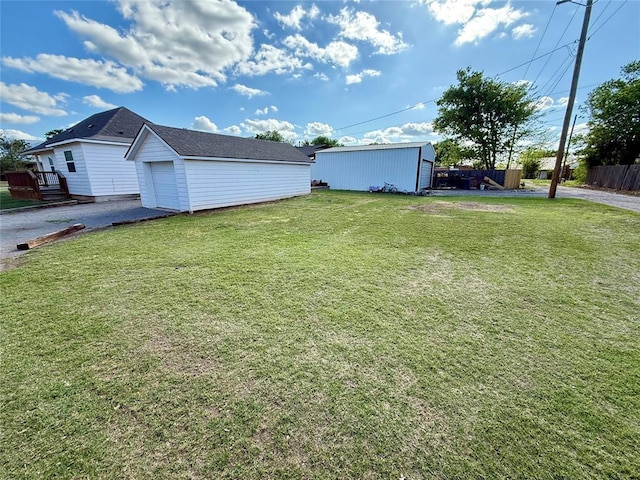 view of yard featuring an outdoor structure, aphalt driveway, and fence