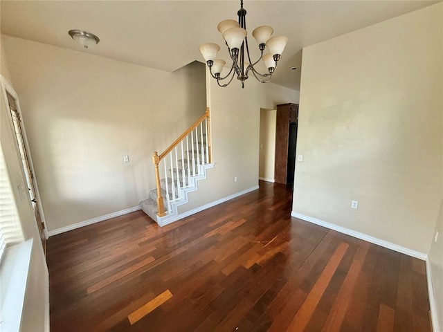 interior space featuring baseboards, a notable chandelier, wood finished floors, and stairs