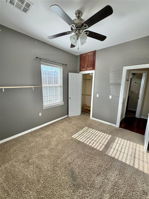 unfurnished bedroom with visible vents, carpet flooring, baseboards, and a ceiling fan