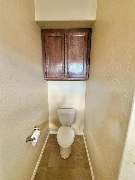 bathroom featuring tile patterned flooring, toilet, and baseboards