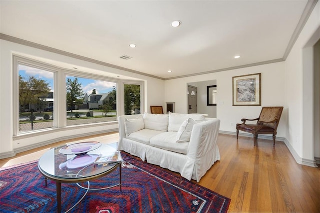 living area featuring light wood-style floors, crown molding, and baseboards