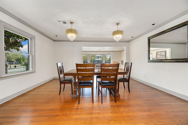 dining area with ornamental molding, a chandelier, visible vents, and light wood-type flooring