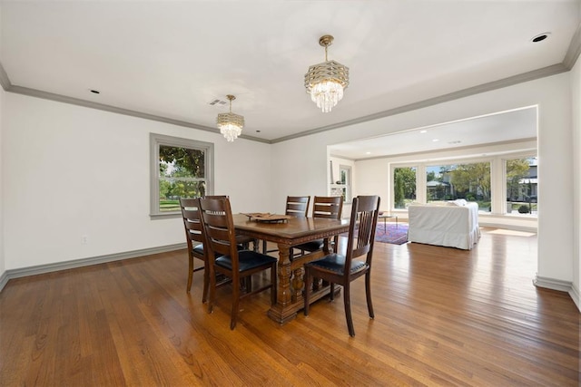 dining room with crown molding, wood finished floors, an inviting chandelier, and a healthy amount of sunlight