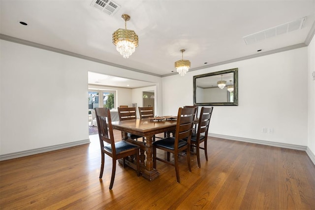 dining area with baseboards, crown molding, a chandelier, and visible vents