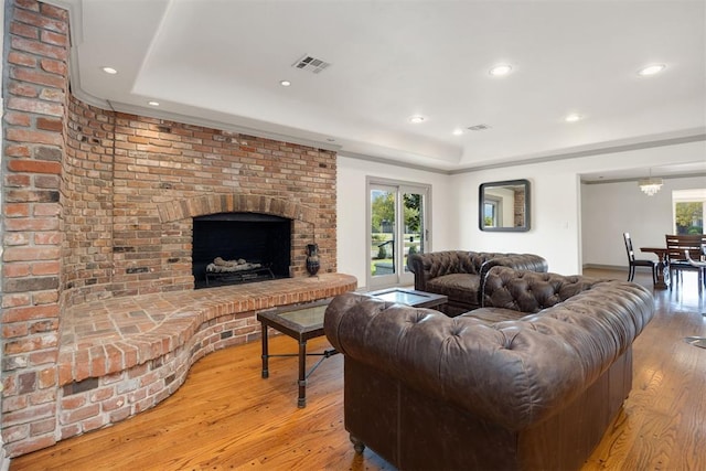 living room featuring a tray ceiling, light wood-style floors, visible vents, and recessed lighting