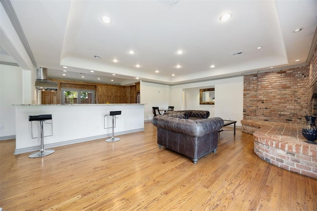 living room with a tray ceiling, recessed lighting, and light wood-style floors