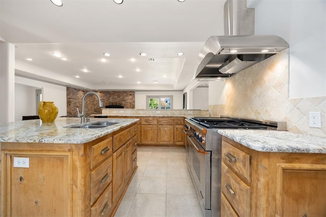 kitchen with stainless steel stove, island exhaust hood, decorative backsplash, and a sink