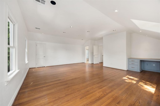 unfurnished living room with recessed lighting, vaulted ceiling, visible vents, wood finished floors, and baseboards