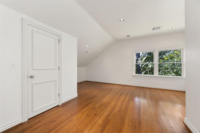 additional living space featuring vaulted ceiling, light wood-type flooring, baseboards, visible vents, and recessed lighting