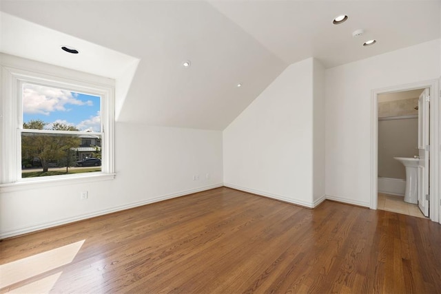 additional living space with a sink, vaulted ceiling, wood finished floors, and baseboards