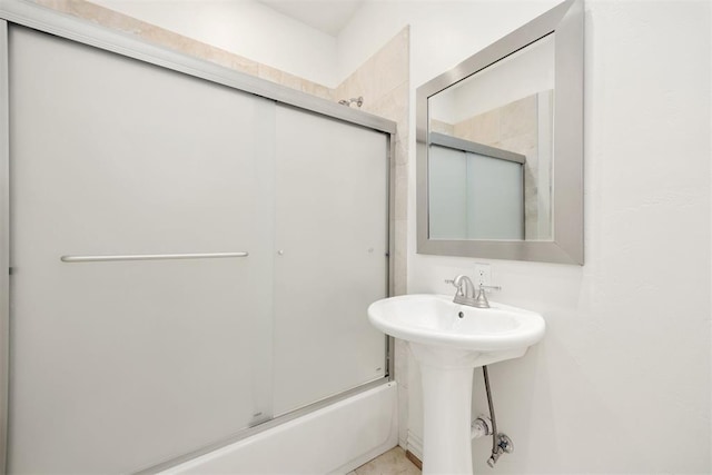 bathroom with bath / shower combo with glass door and a sink