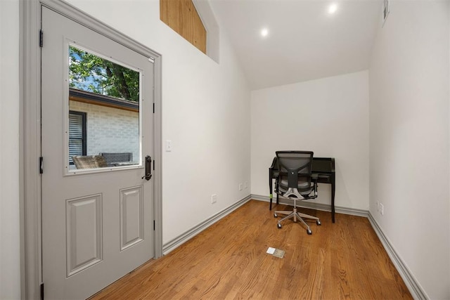 office space featuring baseboards, lofted ceiling, and light wood-style floors