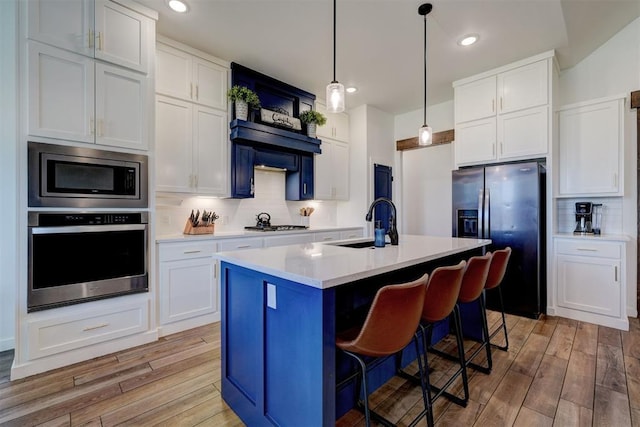 13513 NW 1st St, Yukon, OK 73099 - kitchen with appliances with stainless steel finishes, tasteful backsplash, a sink, and light wood-type flooring