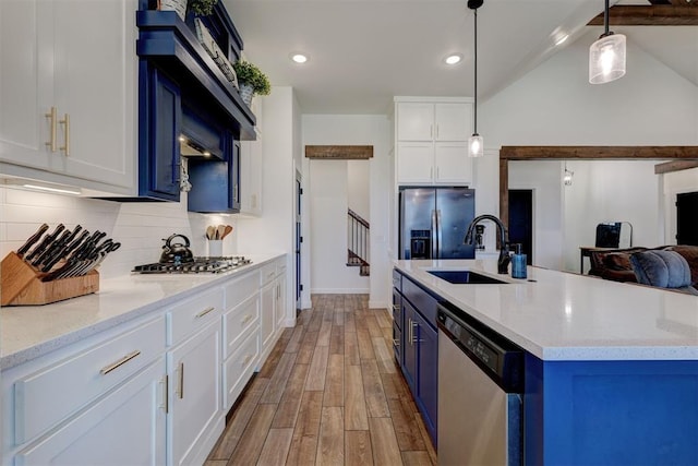 13513 NW 1st St, Yukon, OK 73099 - kitchen featuring backsplash, blue cabinets, a sink, stainless steel appliances, and light wood-style flooring