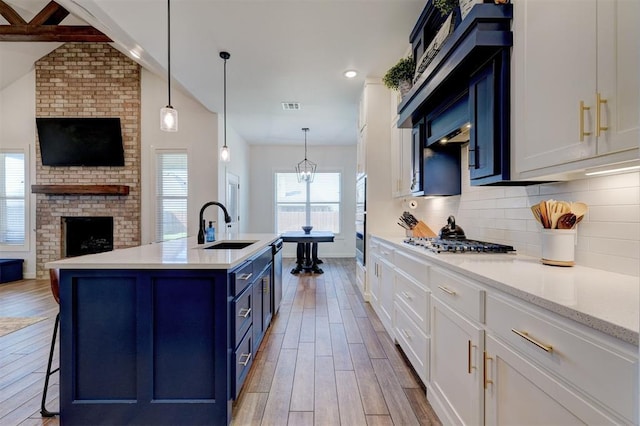 13513 NW 1st St, Yukon, OK 73099 - kitchen featuring open floor plan, a sink, light wood finished floors, appliances with stainless steel finishes, and blue cabinetry