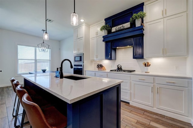 13513 NW 1st St, Yukon, OK 73099 - kitchen with tasteful backsplash, a sink, white cabinets, light wood finished floors, and stainless steel appliances