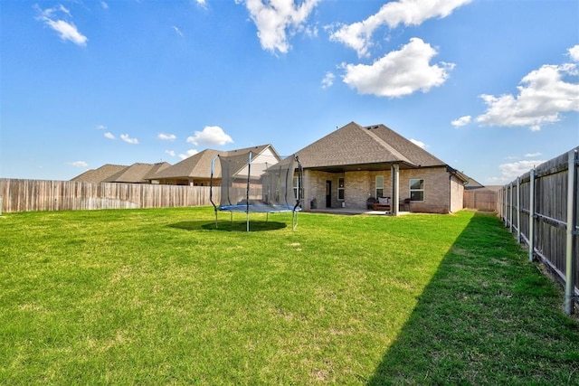 13513 NW 1st St, Yukon, OK 73099 - back of house with a trampoline, brick siding, a fenced backyard, a patio area, and a lawn