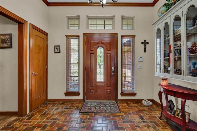 entryway featuring brick floor, baseboards, and ornamental molding