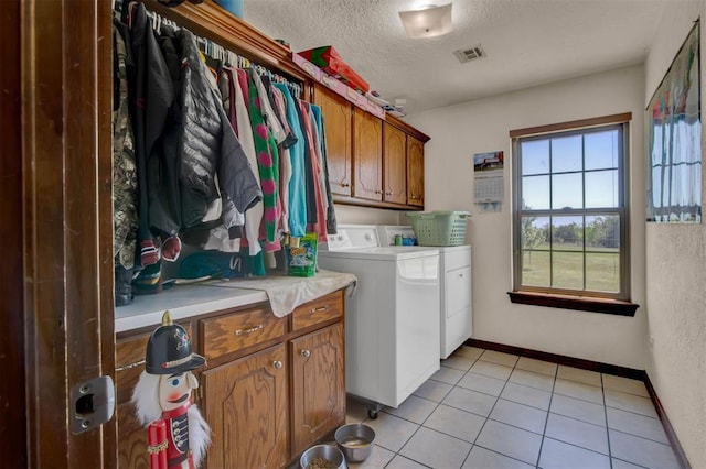 laundry area featuring washer and clothes dryer, a textured ceiling, visible vents, cabinet space, and light tile patterned floors