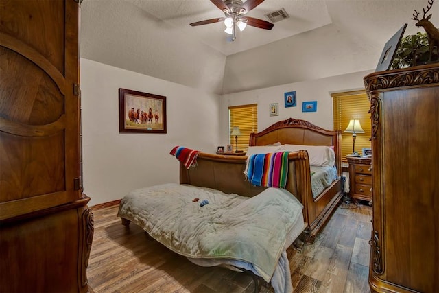 bedroom with a ceiling fan, wood finished floors, a textured ceiling, a raised ceiling, and lofted ceiling