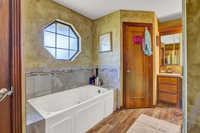 full bath with a bath, vanity, wood finished floors, and tile walls