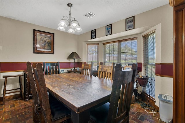 dining room with a chandelier, brick floor, visible vents, and baseboards