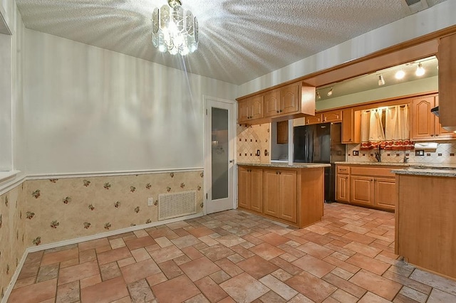 1637 NE 9th St, Moore, OK 73160 - kitchen featuring a textured ceiling, wallpapered walls, a peninsula, baseboards, and freestanding refrigerator