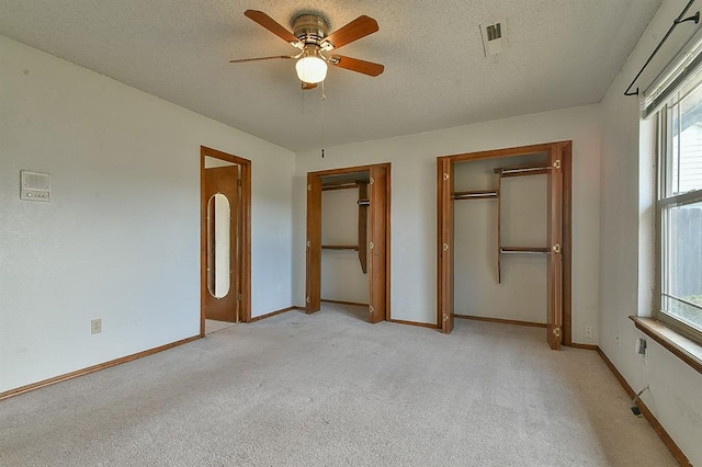 1637 NE 9th St, Moore, OK 73160 - unfurnished bedroom featuring a textured ceiling, multiple closets, light colored carpet, and multiple windows