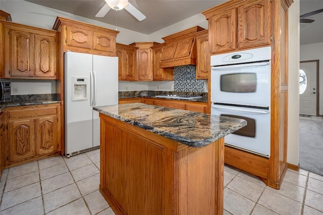 kitchen with a kitchen island, a ceiling fan, white appliances, and light tile patterned flooring