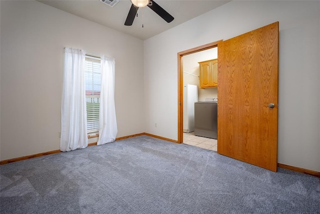 unfurnished bedroom featuring washer / clothes dryer, a ceiling fan, baseboards, and light colored carpet