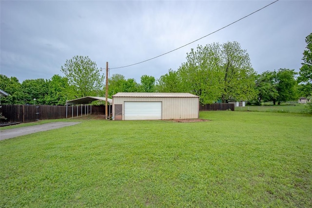 view of yard featuring an outdoor structure, a detached carport, fence, driveway, and a detached garage