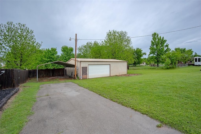 detached garage with fence, a detached carport, and aphalt driveway