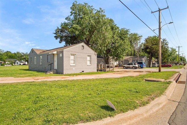 view of side of property with entry steps, a lawn, driveway, and brick siding