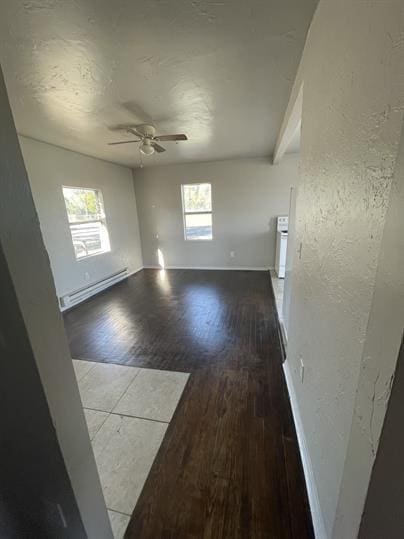 interior space featuring a baseboard radiator, a ceiling fan, wood finished floors, and a wealth of natural light